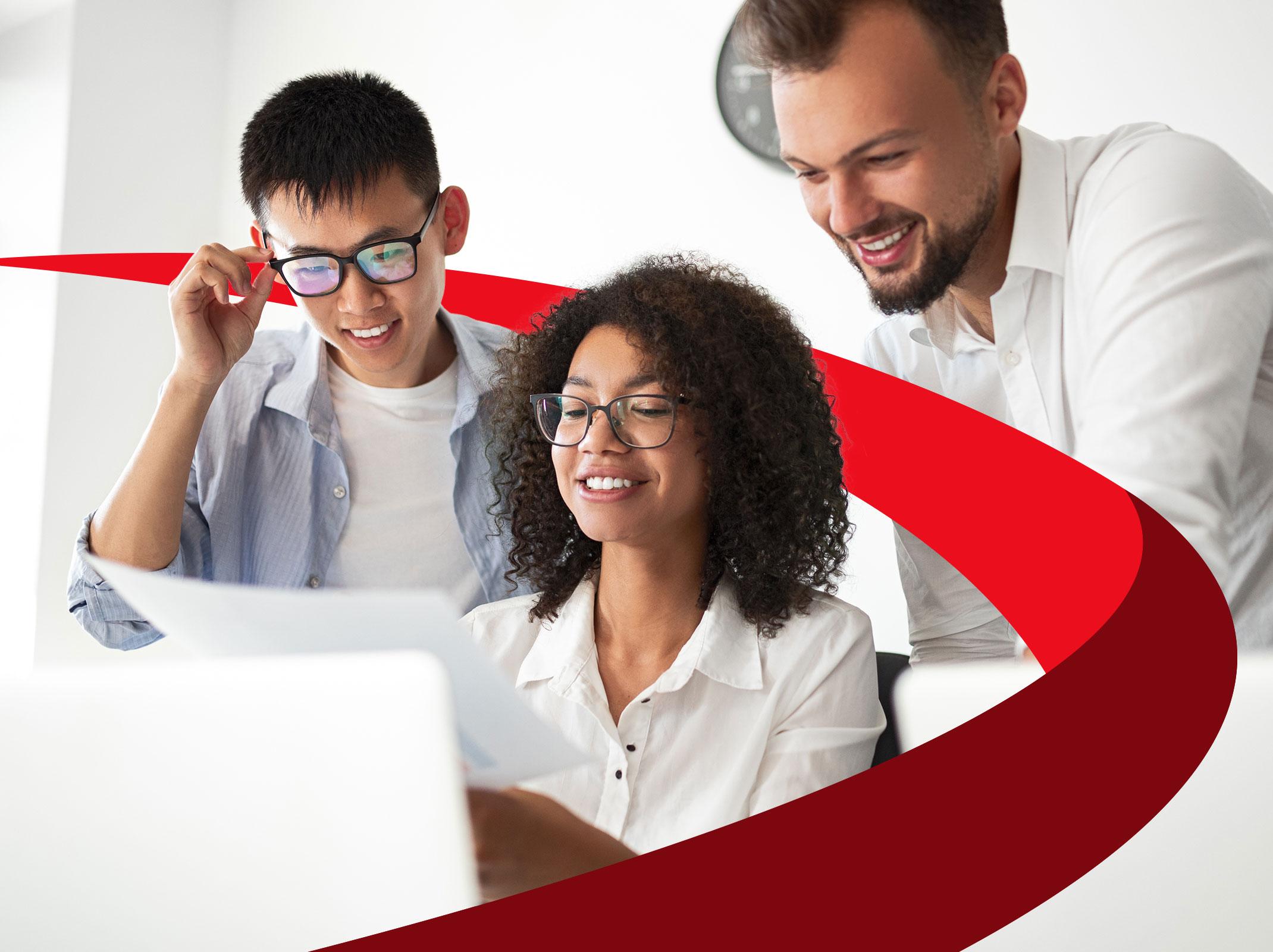 Three analytics professionals reviewing something on a laptop.  They are in an office setting.