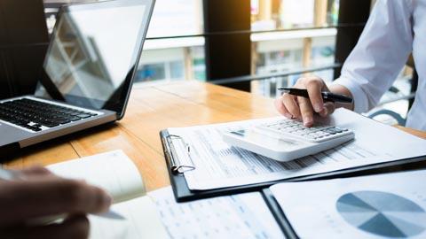 Accounting professional using a calculator and computer in an office setting