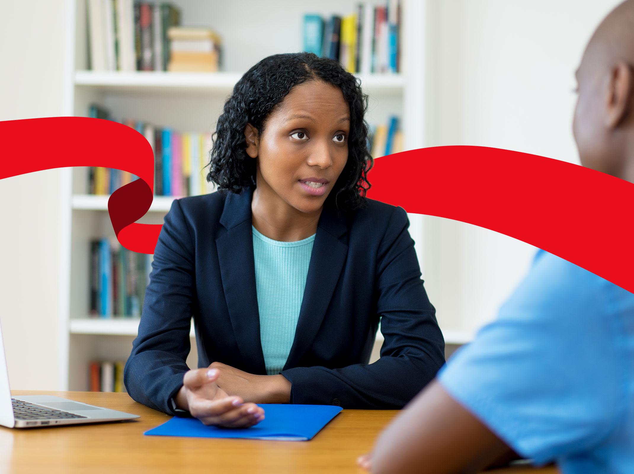 Human Resources professional talking to an employee at a desk in an office setting