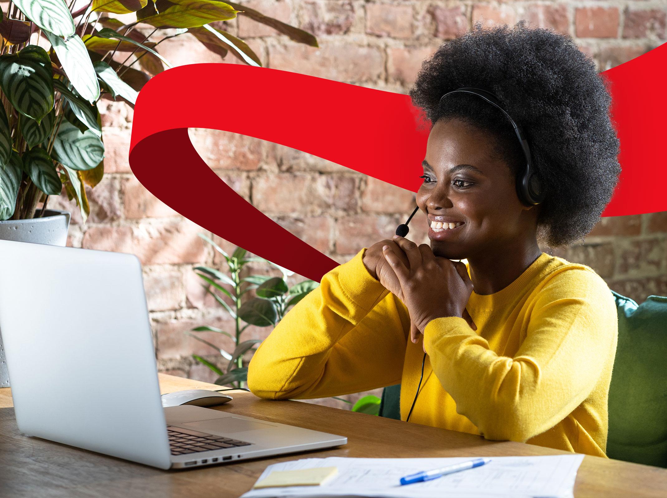 A human resources professional on a virtual meeting in front of a laptop.  She is smiling and appears to be speaking to the individual on the laptop.