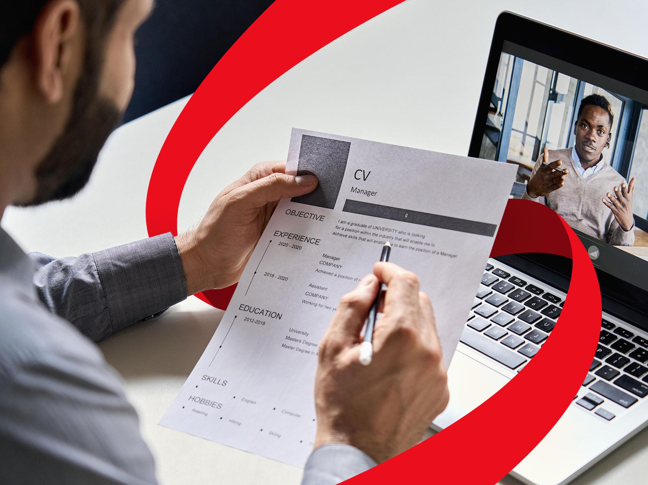 Man looking at a resume while interviewing a candidate via video chat