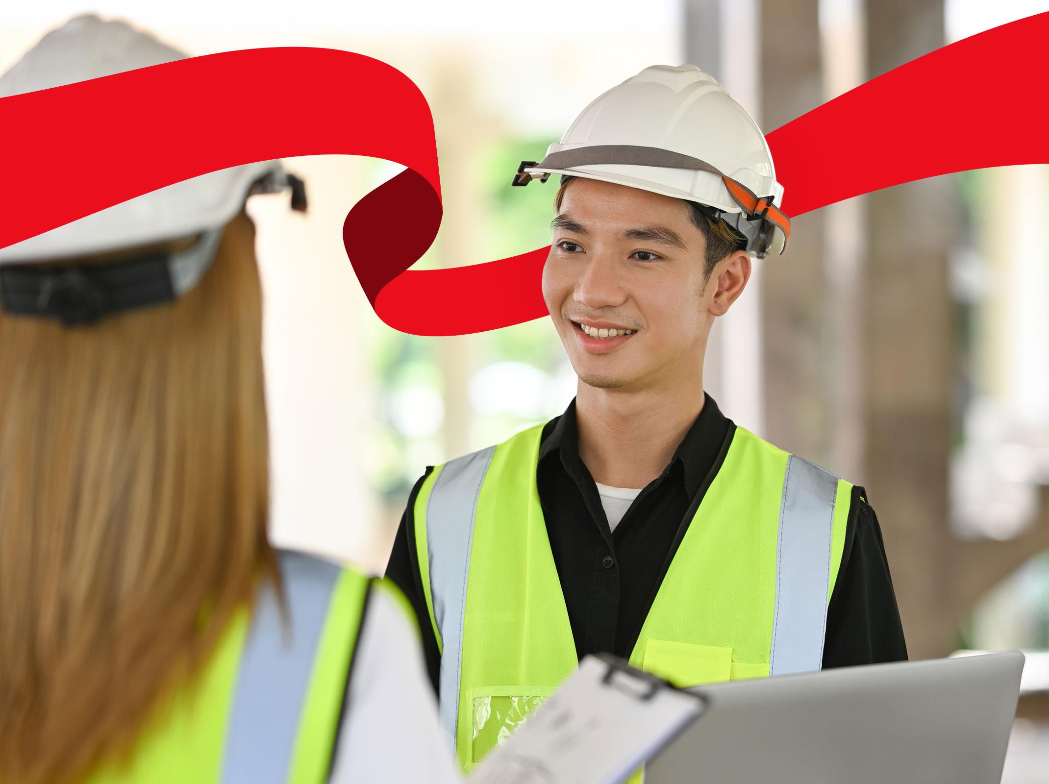 Two people wearing safety gear and talking on a construction site