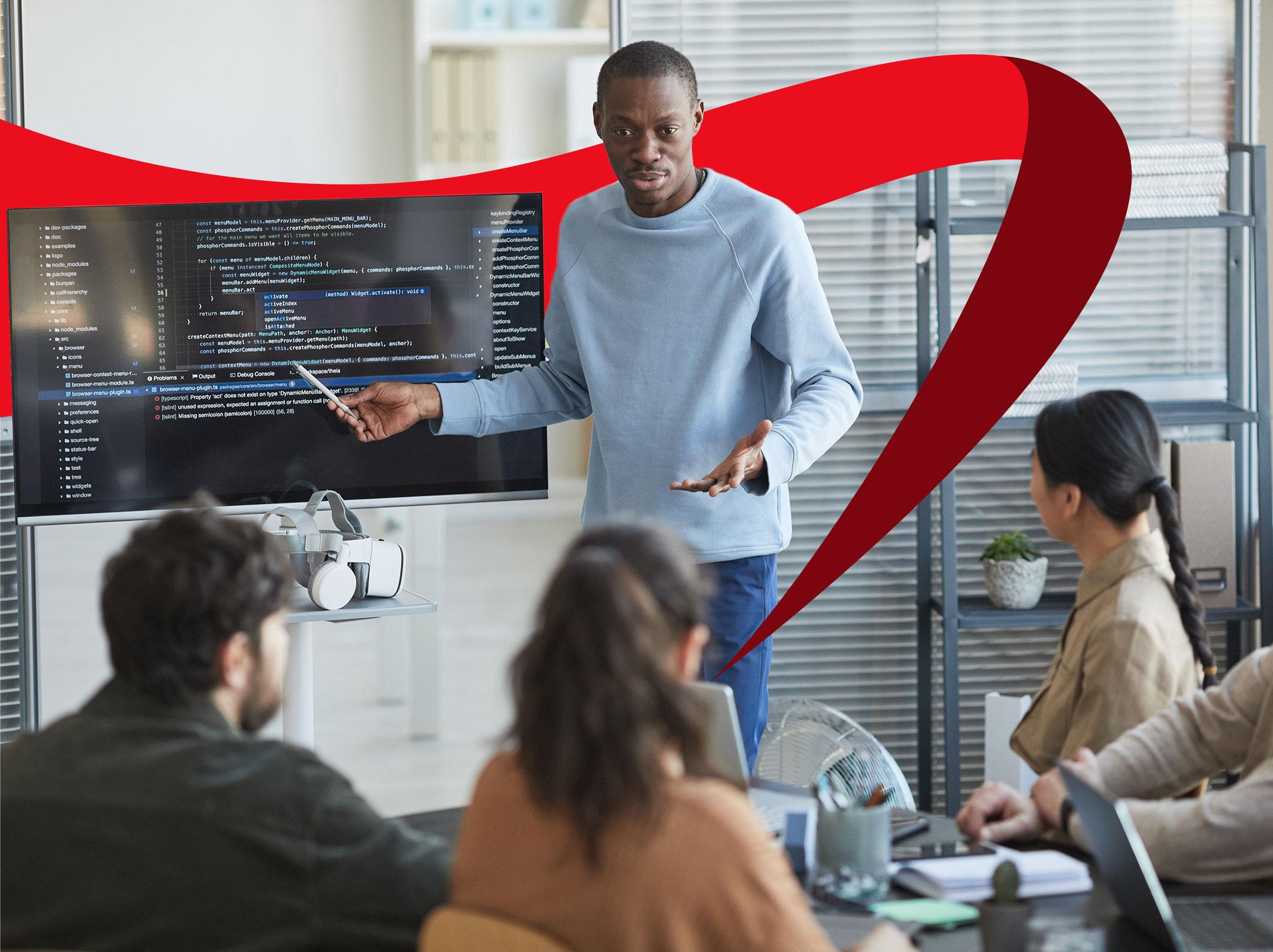 Business professional training others by presenting information on a computer monitor to a group of employees in an office setting