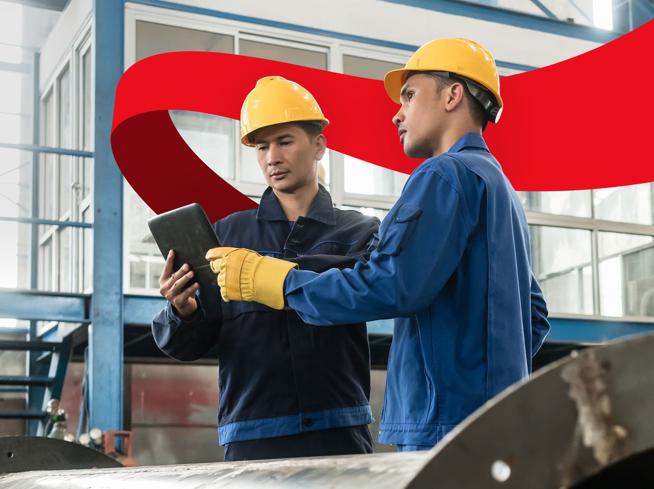 Two factory workers in safety gear looking at a tablet